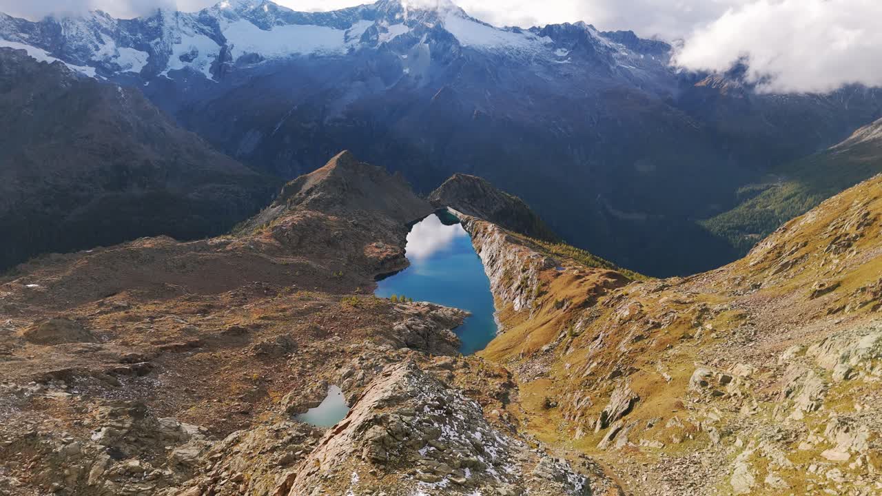 Aerial view of Lago Pirola nestled in the breathtaking Valmalenco Alps, showcasing a serene lake surrounded by mountainous landscapes. Pull Back Shot