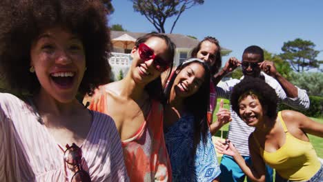 Portrait-of-diverse-group-of-friends-looking-at-camera-and-smiling-at-a-pool-party