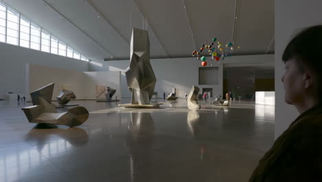 visitor viewing modern sculptures in a spacious art museum