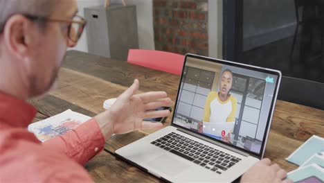 hombre de negocios caucásico en una llamada de video portátil con un colega afroamericano en la pantalla