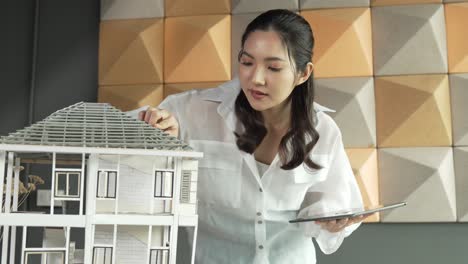 beautiful asian project manager using tablet check house model. manipulator.