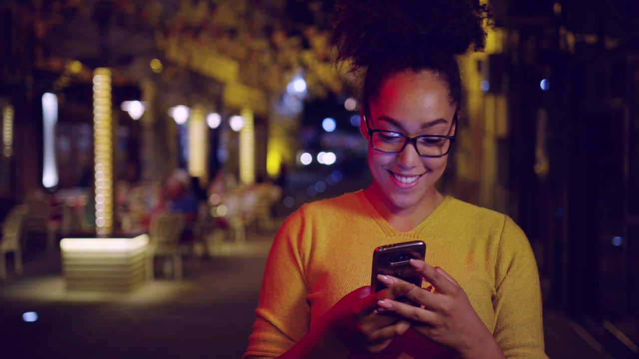 Donna in città di notte che usa lo smartphone