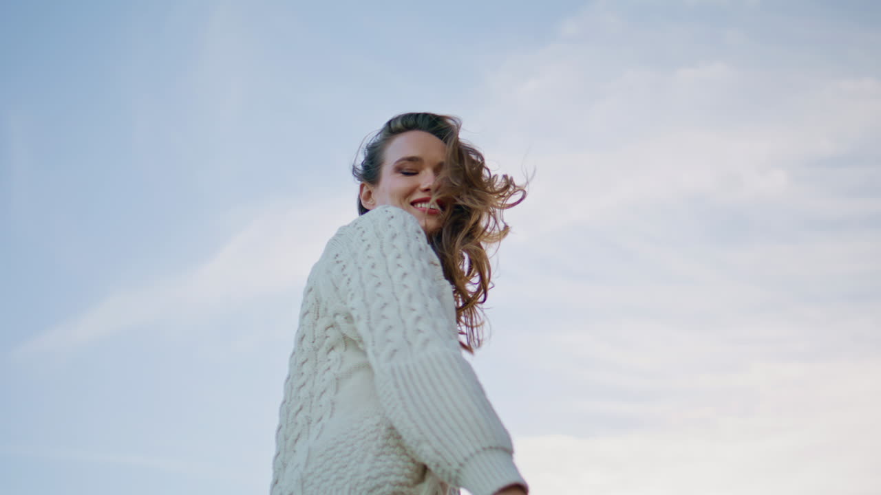 Smiling model adjusting hair posing at evening skyline. Happy brunette relaxing