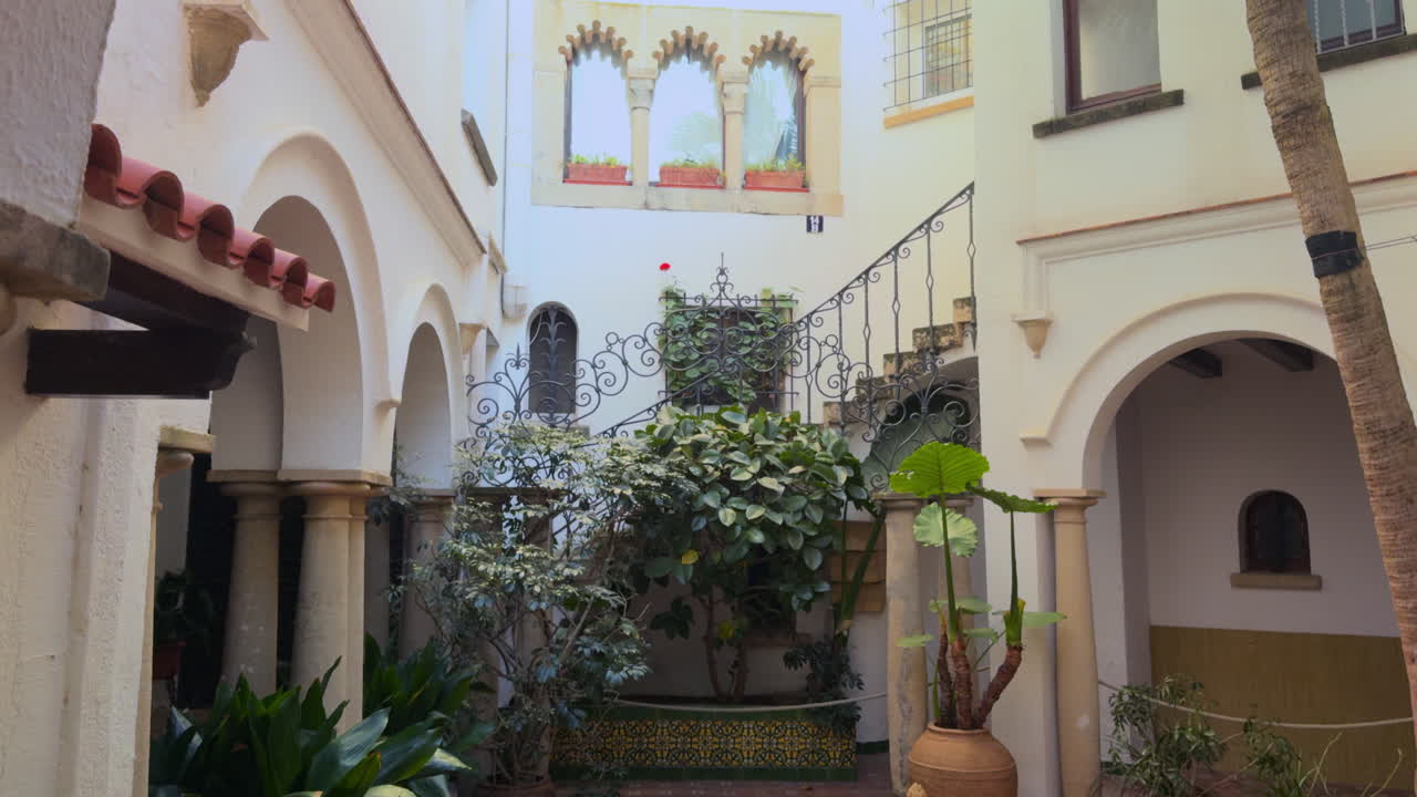 raditional Andalusian-style patio with decorative arches, terracotta flooring, clay pots, iron railings and lush plants. Captured in the coastal village of Roc de Sant Gaietà, Tarragona