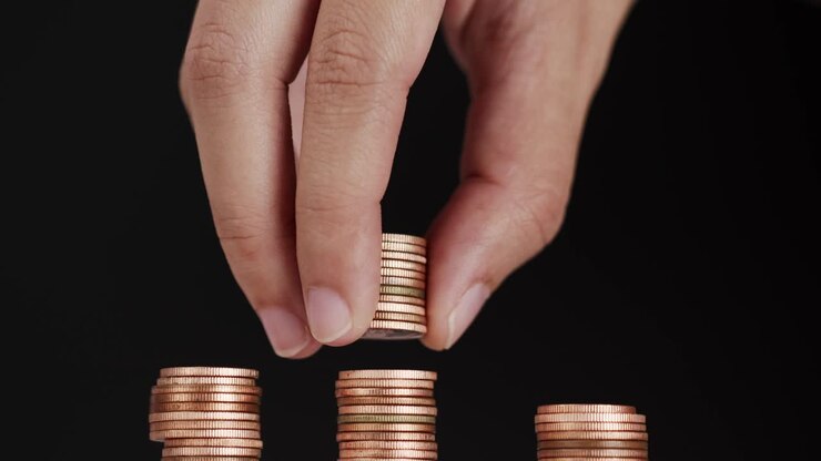 Picking up coins and stacking on pile of coins.