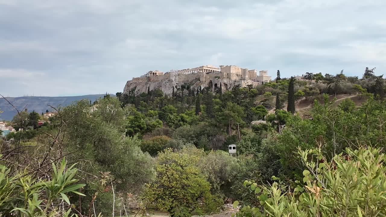 Athens,Acropolis on a cloudy day surrounded by greenery from a distance, fix view.No people