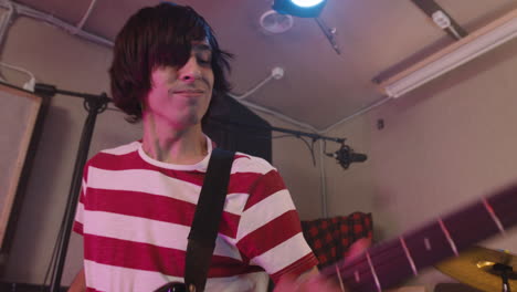 Energetic-Boy-Playing-Guitar-During-A-Band-Rehearsal-In-Recording-Studio-1