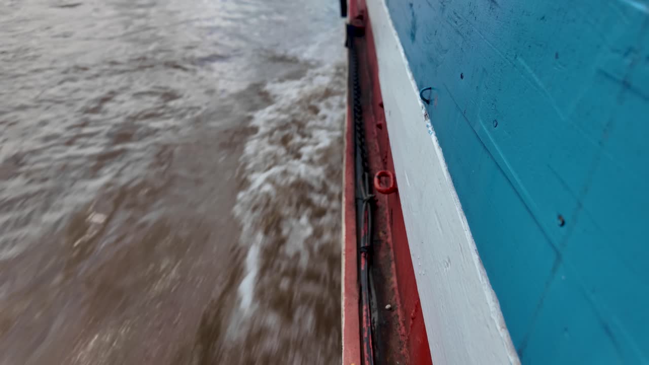 Close view from the boat side showing moving water and lively river scenery on the Mekong
