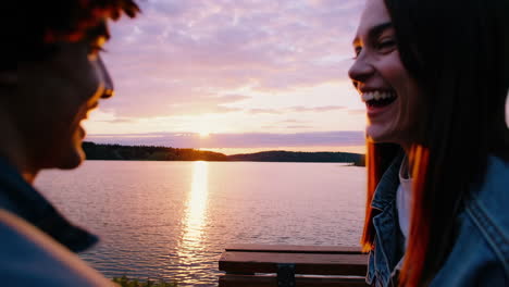 joyful young couple or friends enjoying a beautiful lake sunset