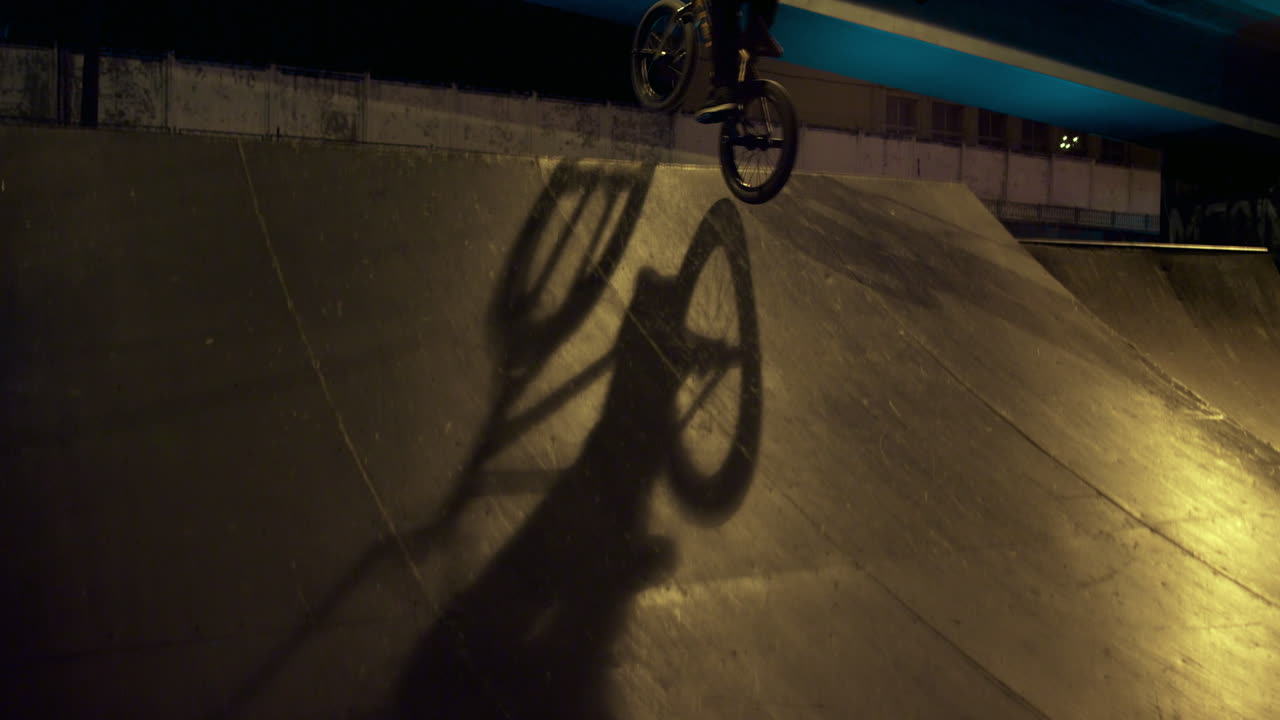 Uomo sportivo in sella a una bicicletta BMX su rampa allo skatepark. Appassionato di sport estremi.