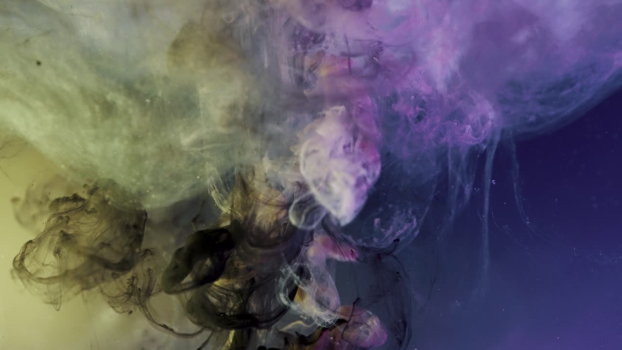 Inchiostro di pittura viola, giallo e nero che si mescola sott'acqua - effetto nebulosa cosmica astratta