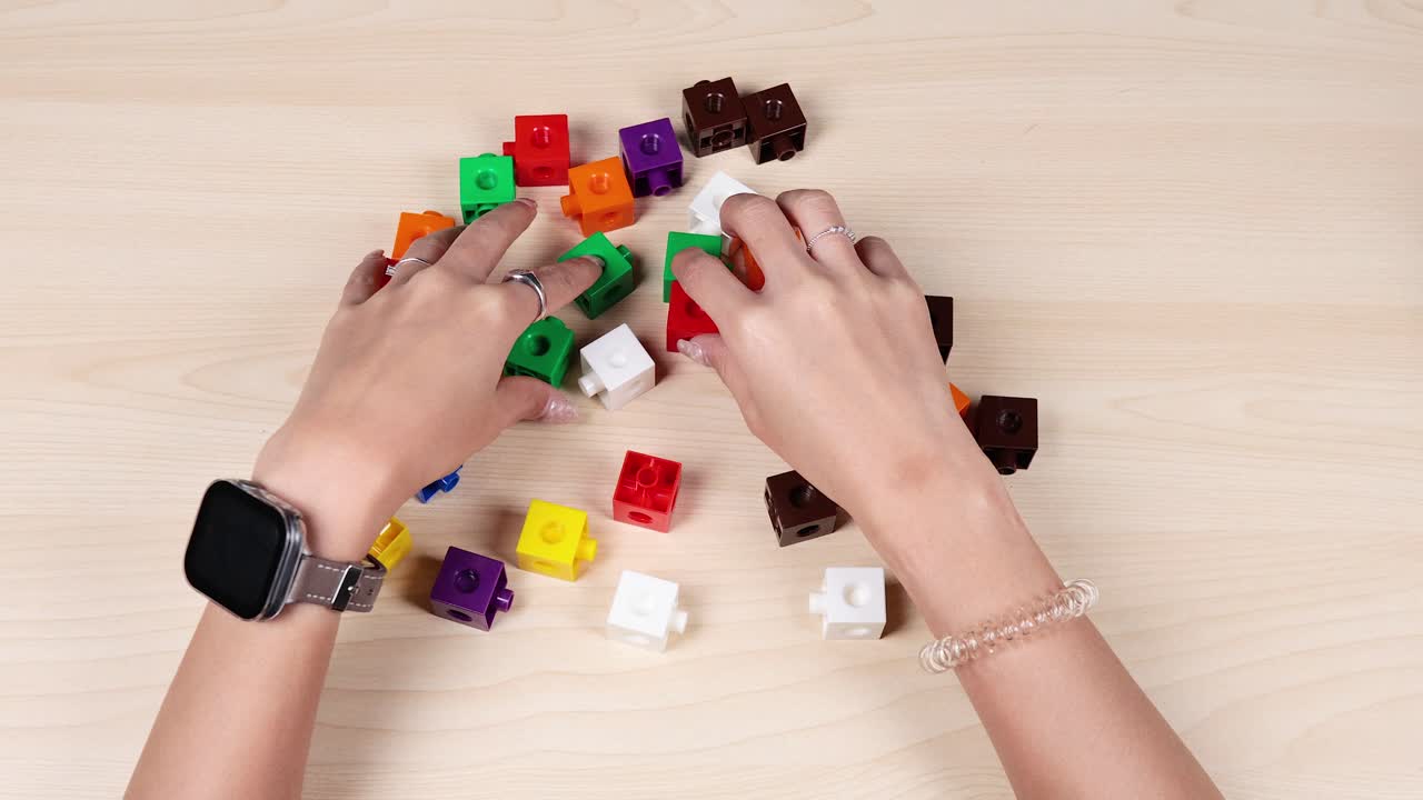 Hands organizing colorful cubes on a table