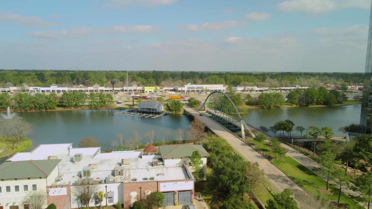Aerial View of a Bridge Over a Lake with a Shopping Center in the Background