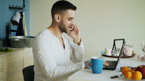 Man working on laptop in kitchen at breakfast
