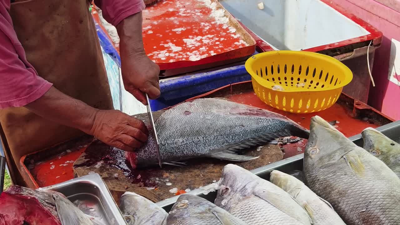 pescador cortando pescado en un mercado