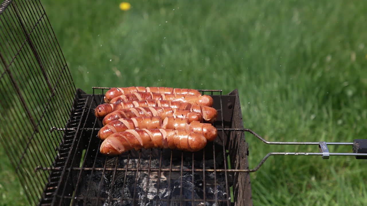 Ready sausages on a grill grate. Cooking barbecue in summer. Grilled sausages for lunch outdoors. Delicious food for picnic.