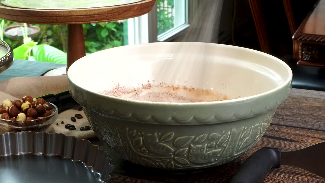 A delicious dessert, Coffee Hazelnut Cream Tart. Made with espresso powder, chocolate crust and loaded with crushed hazelnuts. Great with coffee. Adding ingredients into a large green mixing bowl