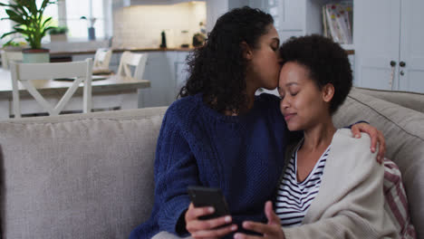 mixed race lesbian couple sitting on couch and
