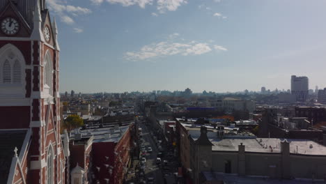 Volar-Hacia-Atrás-Por-Encima-De-La-Calle-En-El-Barrio-Urbano.-Revelando-Torre-Alta-De-La-Iglesia-Católica.-Brooklyn,-Ciudad-De-Nueva-York,-Estados-Unidos