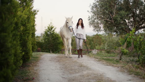 woman walking her white horse