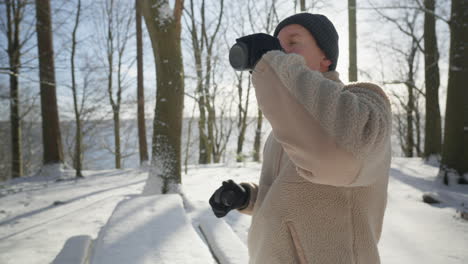 Man-enjoying-a-warm-drink-outdoors-on-a-sunny-winter-day