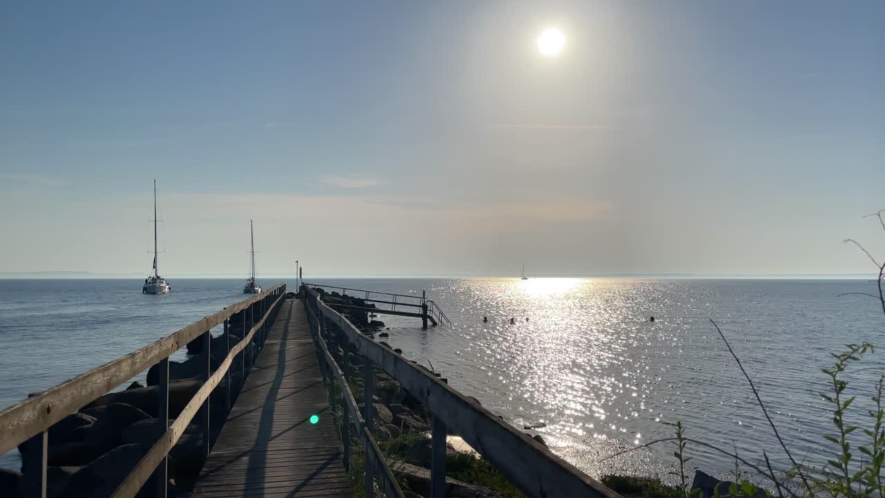 people swiming near sail boat under sunset