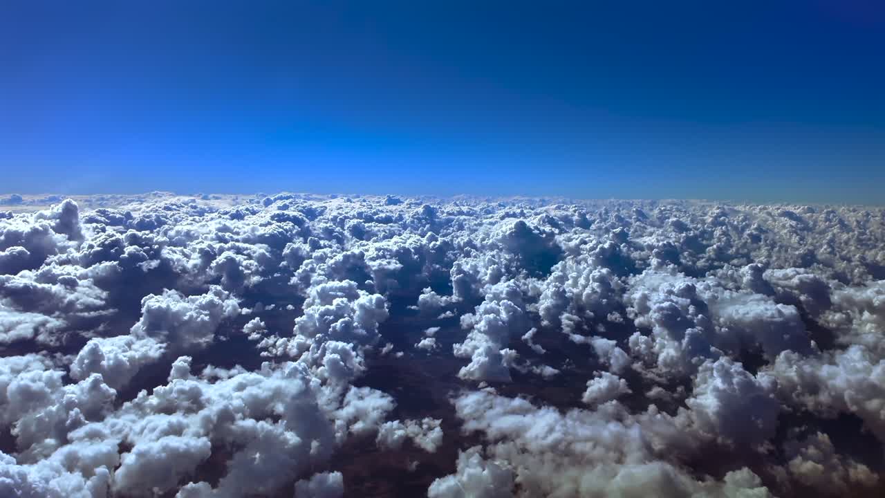 Cockpit view in a peacul flight in the upper atmosphere over cottyny cumulus clouds under a deep blue sky