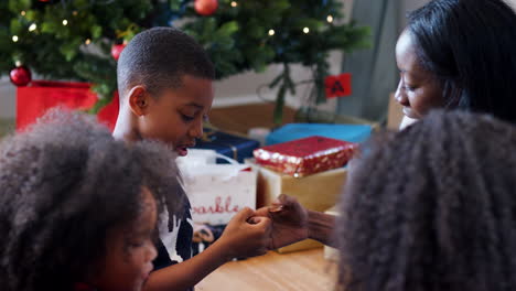 Mutter-Und-Sohn-Spielen-Daumenkrieg,-Während-Die-Familie-Gemeinsam-Weihnachten-Feiert