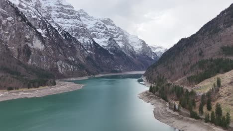 Klöntalersee's-alpine-waters-mirror-the-Glärnisch-massif,-Swiss-alps-aerial