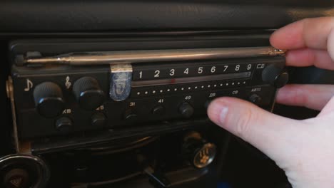 the old radio is tuned by turning the dial in the car. the radio dials the number, looks for stations. old radio of the ussr. human hand