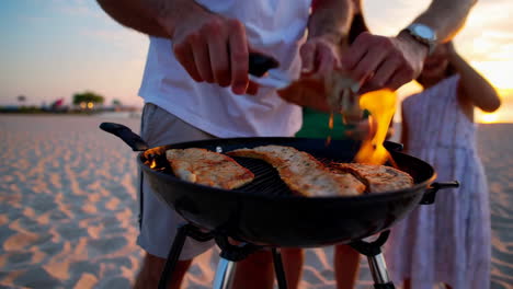 family grilling on the beach at sunset