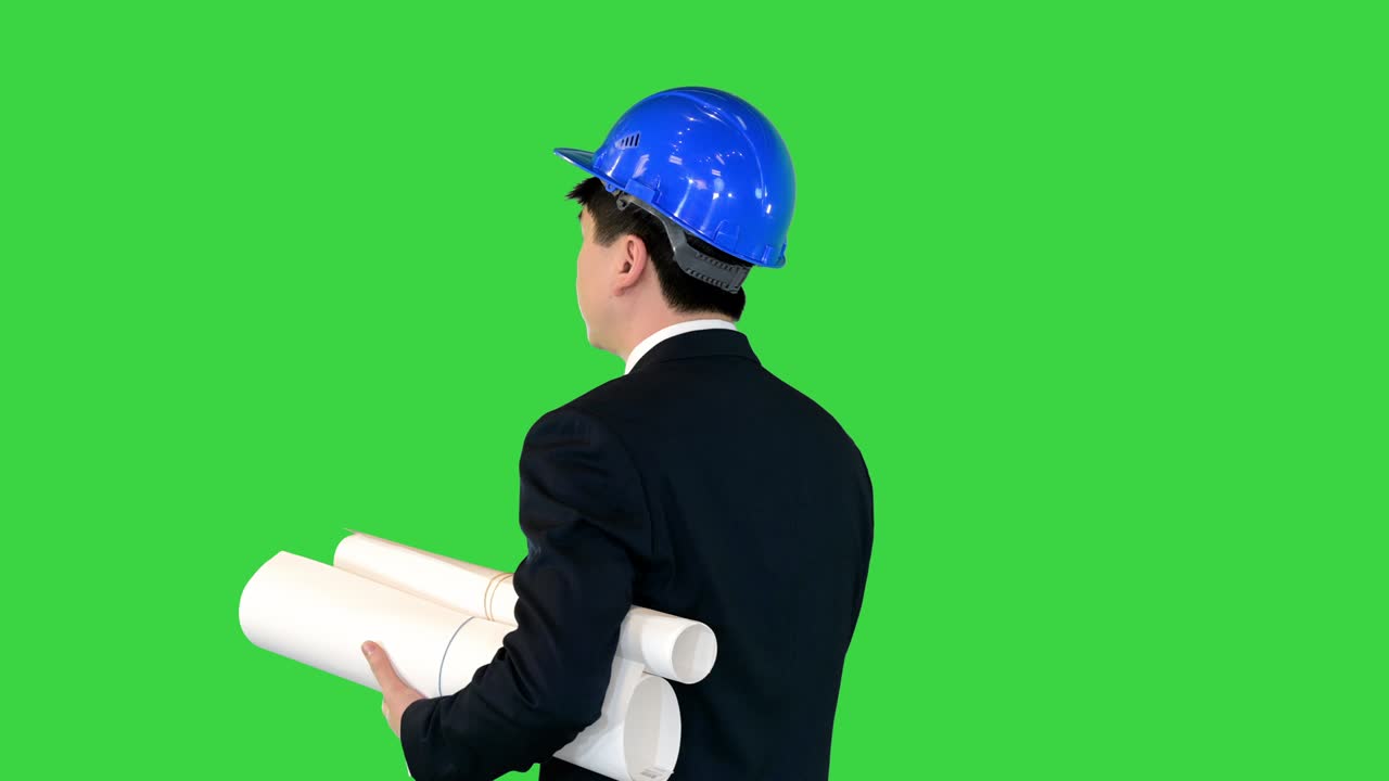 젊은 남성 건축가가 녹색 스크린, 크로마 키에 블루프린트를 가지고 고 있습니다.