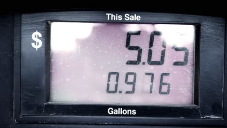 gas station pump prices high over 5 five dollars per gallon 5.15 regular starting at 0 dollars up to 28 dramatically zooming panning and moving around a dirty grimy gas station gallons sale screen