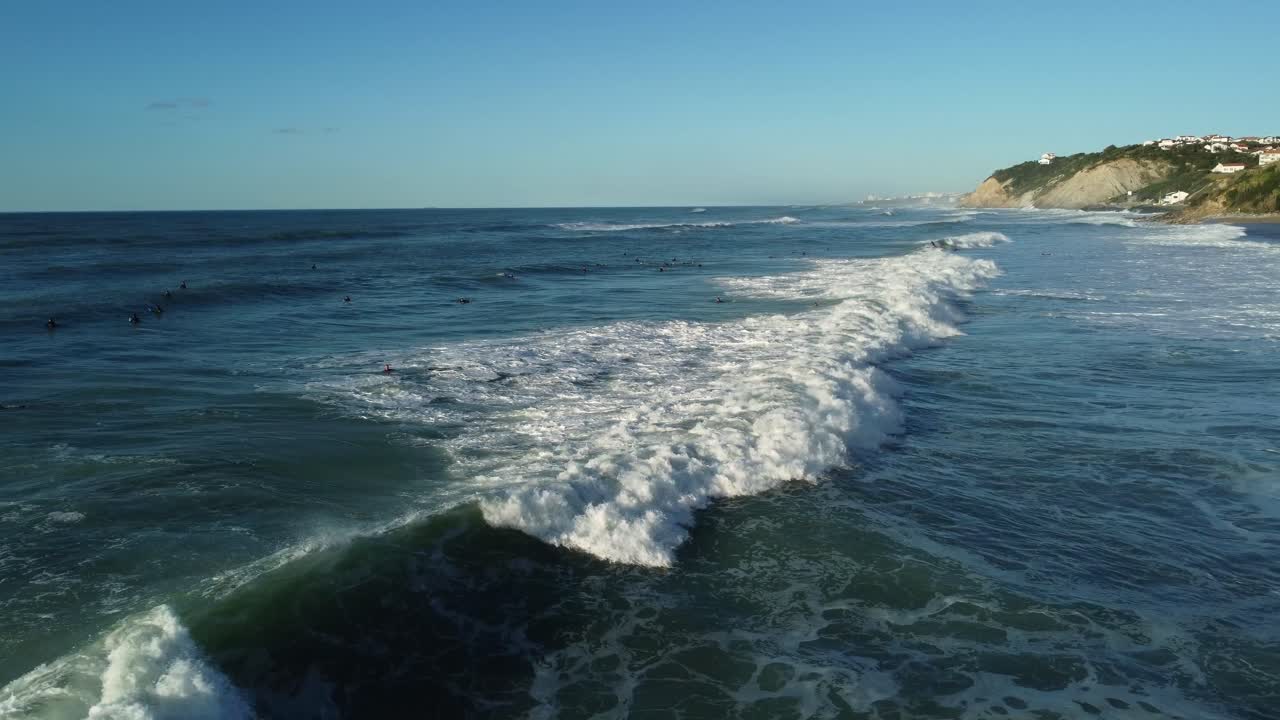 Ocean waves with surfers near the coastline