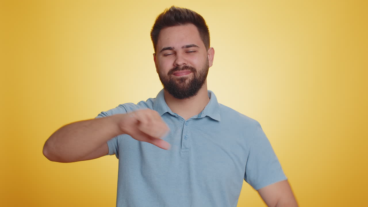 Upset handsome man guy in tshirt showing thumbs down sign gesture disapproval dissatisfied dislike