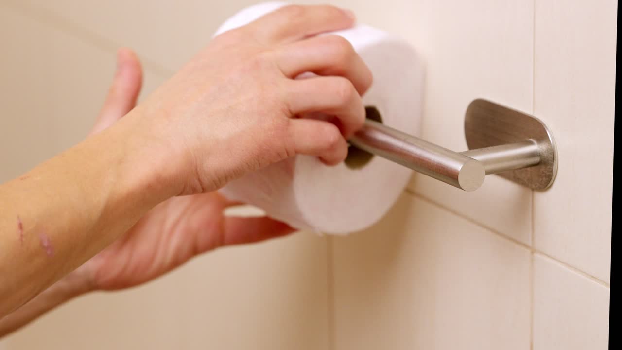 Man replacing empty toilet paper roll in bathroom