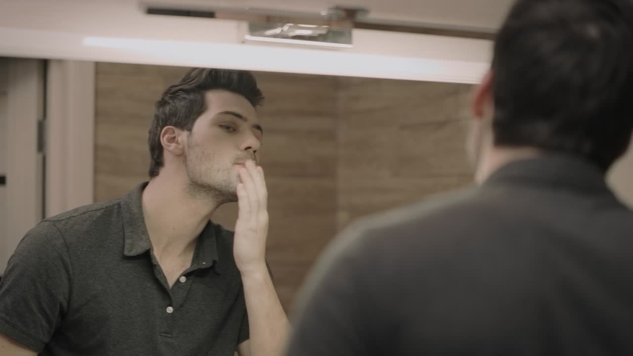 섹시한 남자가 술집의 거울 앞에서 반사되고 있습니다.