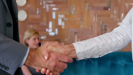 Mid-section-of-woman-shaking-hands-with-businessman-and-exchanging-visiting-card