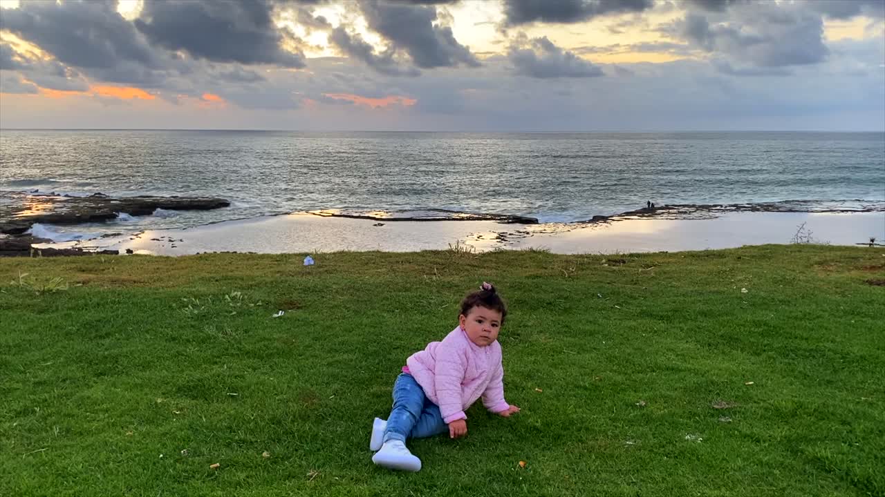 Little cute adorable toddler girl playing on the beach during golden hour