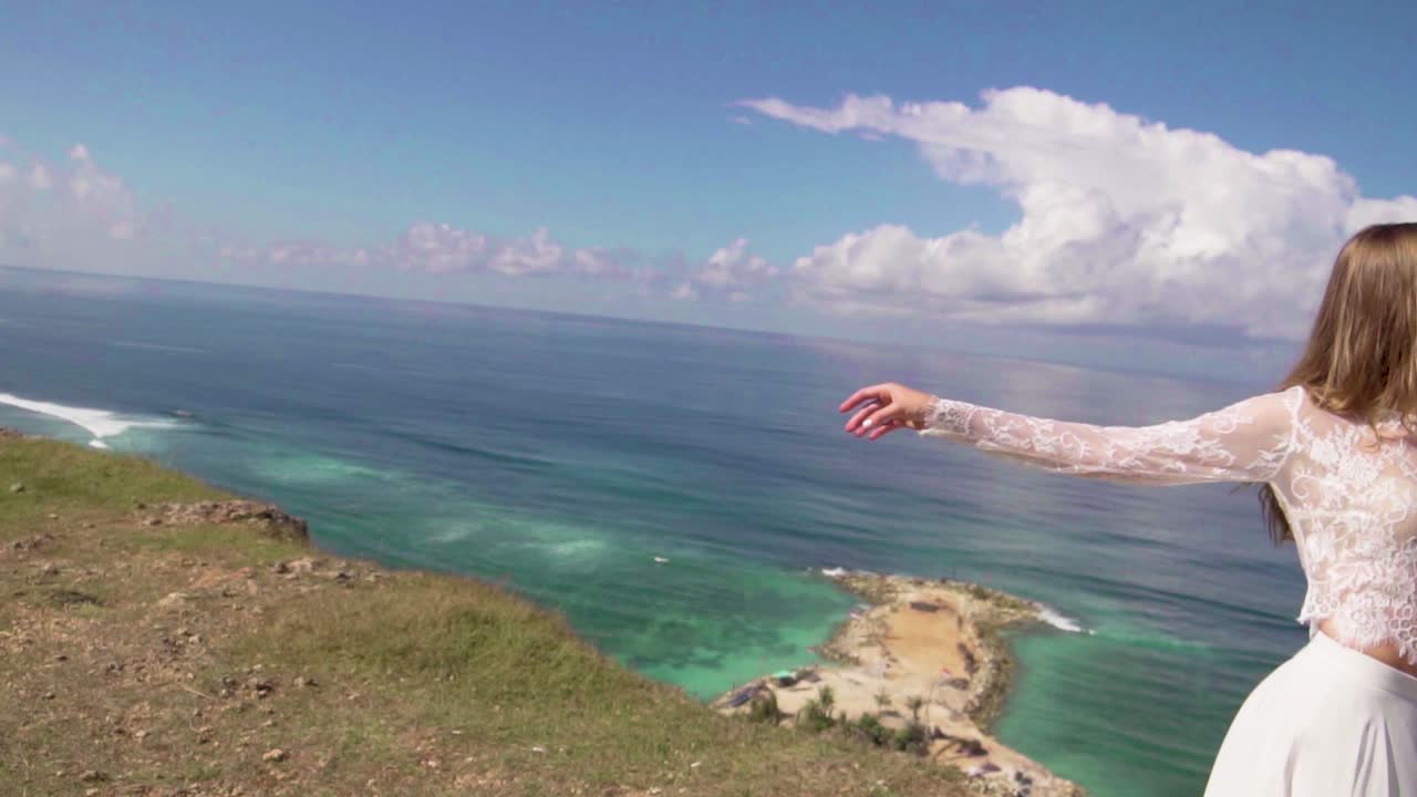 바다가 보이는 바람에 펄럭이는 하얀 드레스를 입은 예쁜 젊은 신부