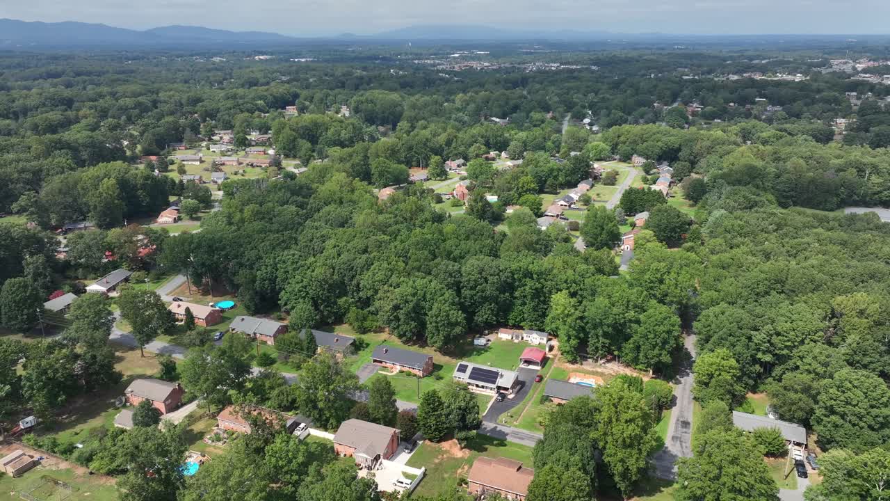 Suburb neighborhood with single family house and solar panels on roof. Pool in garden during hot summer day in Virginia. Green forest trees in middle class residential area of town. Aerial top down