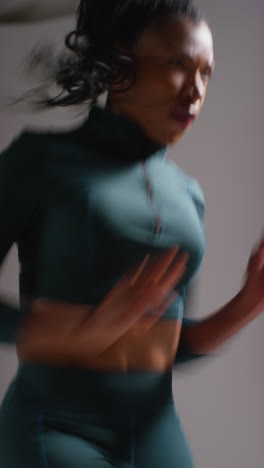 vertical video close up studio shot of female athlete wearing tracksuit training running on the spot and recovering after exercise 1