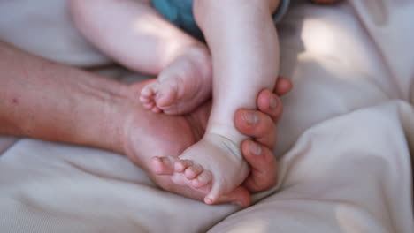male hand holding tiny feet of a baby. caucasian dad stroking his infant's foot. close up.