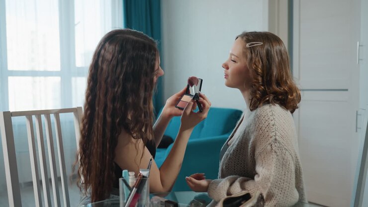 Amici che mescolano cosmetici al tavolo, gruppo di amici impegnati in una sessione pratica e tutorial di make-up, momento informale di amici che condividono consigli di bellezza e applicano il trucco alla luce naturale