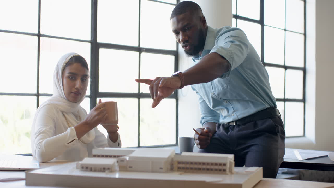 Discussing architectural model, business colleagues collaborating in modern office