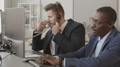 two diverse stock traders in headsets talking to clients