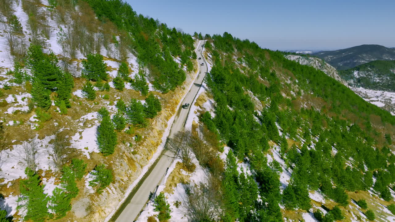 Aerial view of cars driving on a winding mountain road in winter