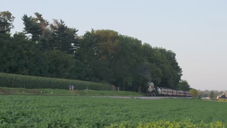 A-1924-Steam-Engine-with-Passenger-Train-Puffing-Smoke-Traveling-Along-the-Amish-Countryside-on-a-Summer-Day