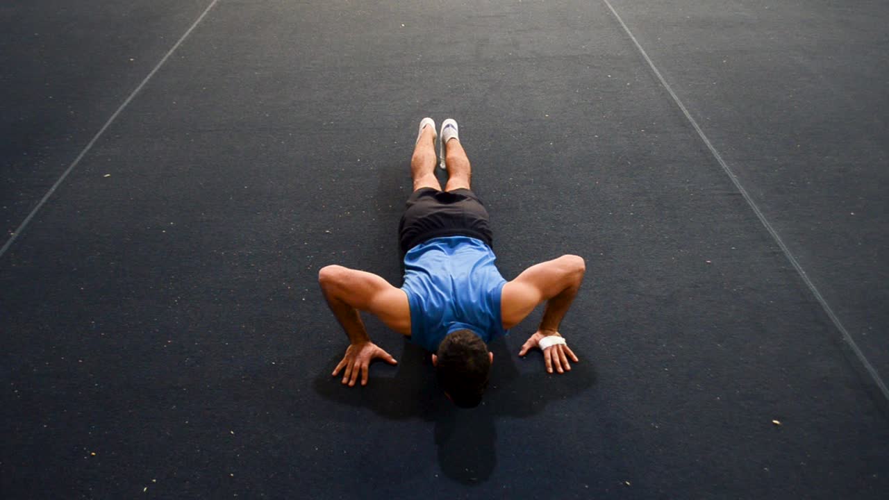 un tipo haciendo un tipo especial de flexión hacia arriba en una vista frontal superior aún fotografiada dentro de un gimnasio de gimnasia