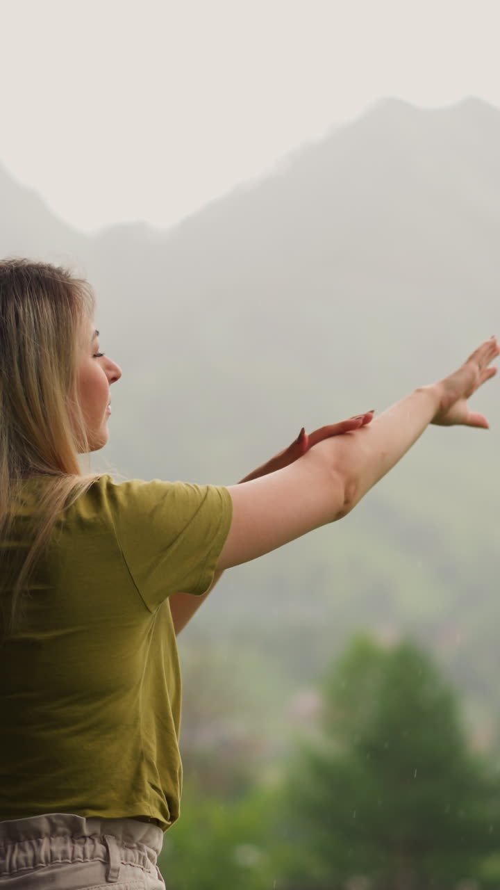 mujer feliz con cabello rubio se lava las manos bajo el agua de la lluvia pasando tiempo en el hotel highland eco resort en un día nublado vista cercana en cámara lenta